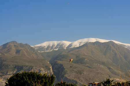 paroplan is flying in the sky on the mountains on a sunny dayのeditorial素材