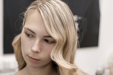 Blonde girl with long hair in a beauty salon with wave hairstyle for promの写真素材