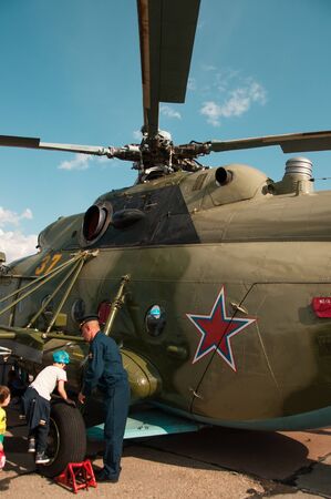 Chelyabinsk, Shagol village, Russia September 14, 2019: Close-up Russian helicopter on the viewing platform at the Aviation festival, a man in uniform helps children climb a helicopter on a sunny autumn dayのeditorial素材