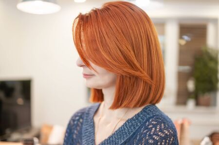 Portrait of a woman with bright red hair and haircut square close-up