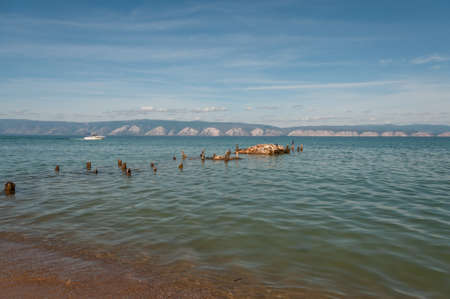 Lake Baikal with a view of the water stones and birds Cormorant and the opposite mountainous shore on a summer sunny dayの写真素材