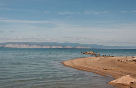 Lake Baikal with a view of the water stones and birds Cormorant and the opposite mountainous shore on a summer sunny dayの写真素材