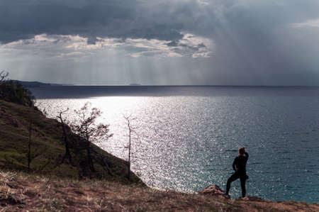 Woman looks at a picturesque view of Lake Baikal and the sun's rays falling on the waterの写真素材