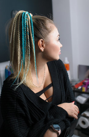 Blonde woman with gathered hair in ponytail and with braids hair accessory in profile indoorsの写真素材