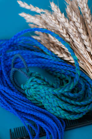 Decorative blue hair accessory, elastic band with small colored braids, handmade close-upの写真素材