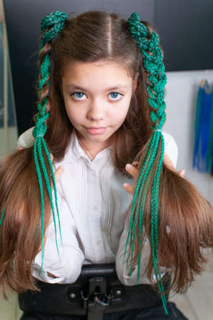 Teenager girl with colored pigtails in profile indoorsの写真素材