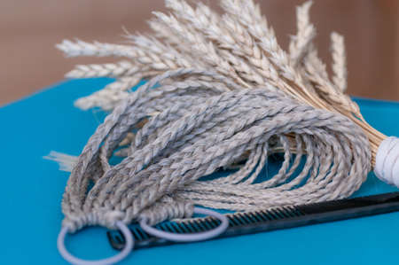 Decorative hair accessory of natural light color, elastic band with small colored braids, handmade close-upの写真素材