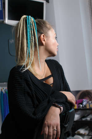 Blonde woman with gathered hair in ponytail and with braids hair accessory in profile indoorsの写真素材