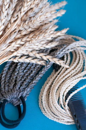 Decorative hair accessory of natural light color, elastic band with small colored braids, handmade close-upの写真素材
