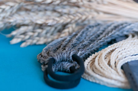 Decorative hair accessory of natural light color, elastic band with small colored braids, handmade close-upの写真素材
