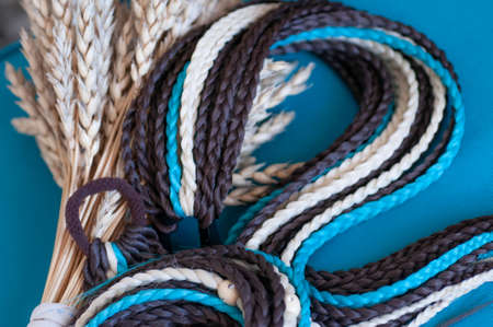 Decorative hair accessory of brown blue color, elastic band with small colored braids, handmade close-upの写真素材