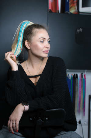 Blonde woman with gathered hair in ponytail and with braids hair accessory in profile indoorsの写真素材