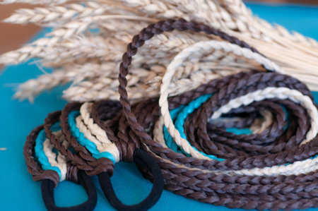 Decorative hair accessory of brown blue color, elastic band with small colored braids, handmade close-upの写真素材