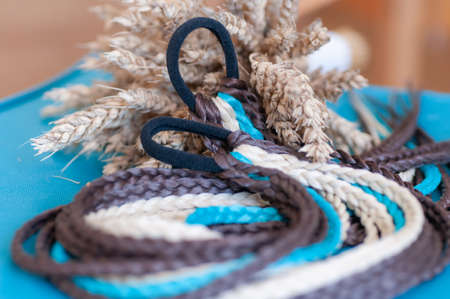 Decorative hair accessory of brown blue color, elastic band with small colored braids, handmade close-upの写真素材