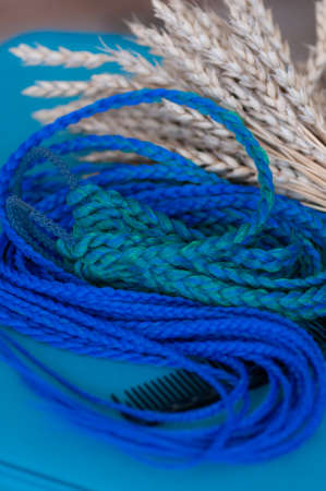 Decorative blue hair accessory, elastic band with small colored braids, handmade close-upの写真素材