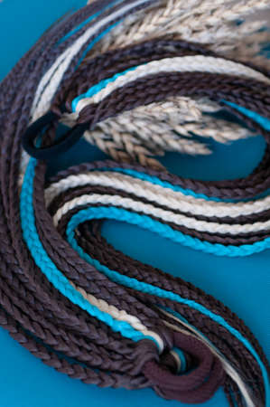 Decorative hair accessory of brown blue color, elastic band with small colored braids, handmade close-upの写真素材