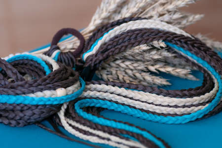 Decorative hair accessory of brown blue color, elastic band with small colored braids, handmade close-upの写真素材