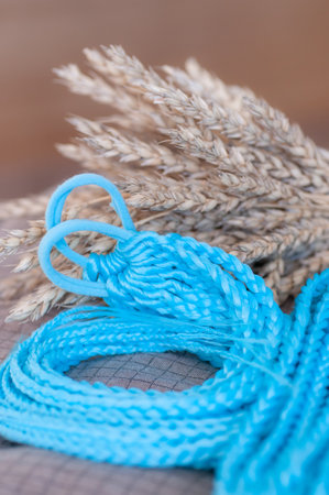 Decorative blue hair accessory, elastic band with small colored braids, handmade close-upの写真素材