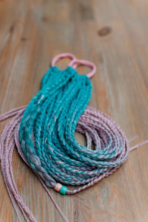 Colored braids made of pink and blue artificial hair on a hand-made cutter close-up