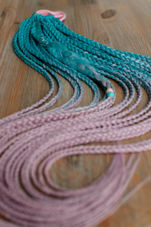 Colored braids made of pink and blue artificial hair on a hand-made cutter close-up