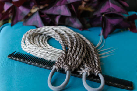 Accessory for long hair from small colored braids with an elastic hair band in assortment on a wooden tableの写真素材