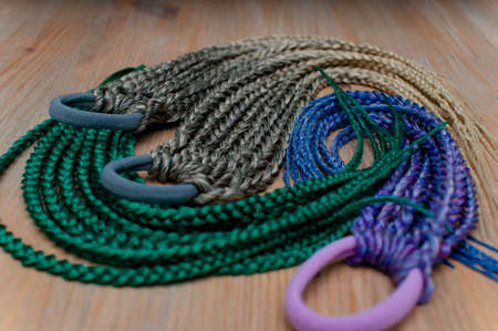 Accessory for long hair from small colored braids with an elastic hair band in assortment on a...