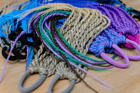 Accessory for long hair from small colored braids with an elastic hair band in assortment on a wooden tableの写真素材