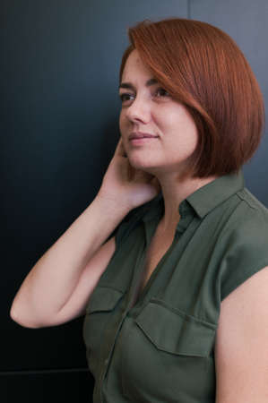 Portrait of woman with red natural hair and bob haircut in casual clothes without makeup in a beauty...