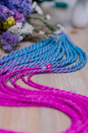 Colored braids, hair accessory on an elastic band on a wooden background close-upの写真素材