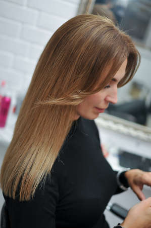 Woman with beautiful long brown hair in profile in a beauty salonの写真素材