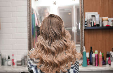 Hollywood curls on a young blonde woman in a beauty salon, view from the backの写真素材