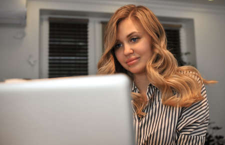 Blonde woman working at the computer at homeの写真素材