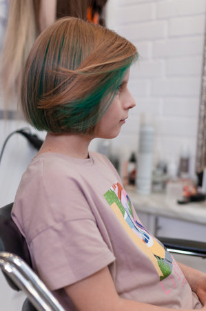 Teenage girl with colored green hair in a bob hairstyle in profile, close-up indoorsの写真素材