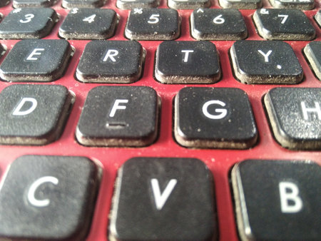 photo of a dusty black keyboard on a red laptop. Part of a laptop keyboard, close up. Dusty keyboard...