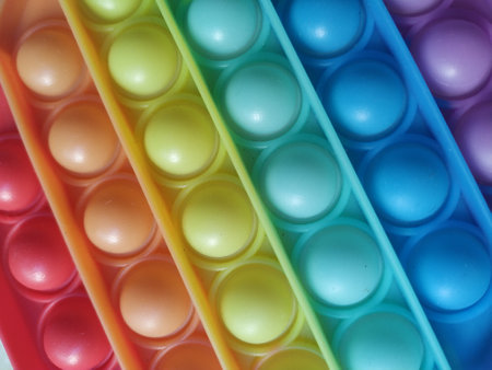 Rainbow Pop it fidget toy on a floor in home. Fidget popper, anti anxiety and stress relief gameの写真素材