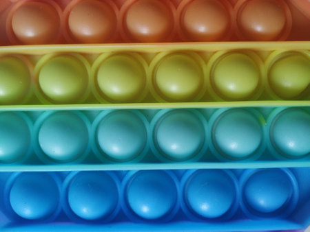Rainbow Pop it fidget toy on a floor in home. Fidget popper, anti anxiety and stress relief gameの写真素材