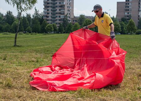 Saint-Petersburg, Russia - June 26, 2016: Kite Festival in the town of Pushkin. Man preparing to launch a red kite.のeditorial素材