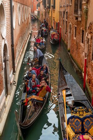 Venice, Italy - October 13, 2017: Gondoliers take tourists through the narrow canals of Venice. Tourists of their China. The tourist is photographed on the phone.のeditorial素材