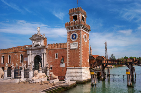 Historic shipyard, Arsenal, gate and the channel. Venice, Italy. The gate is richly decorated with sculptures. bove the gate is a sculpture of a Venetian lion. There's a clock on the tower.の写真素材
