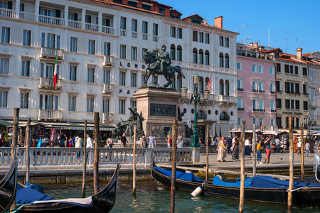 Venice, Italy - 07 May 2018: View to Riva degli Schiavoni waterfront with Equestrian Statue of King Victor Emmanuel II and tourists resting and walking. In the foreground Venetian gondolas.のeditorial素材