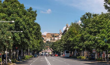 Bergamo, Italy - May 10, 2018: Street and traffic in center of city with Bell tower in front and...