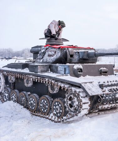 Krasnoye Selo, St. Petersburg, Russia - January 19, 2019: Military historical reconstruction - the battle for Leningrad. Tank PzKpfw III is preparing for battle. Tankman climbs into the tank.のeditorial素材