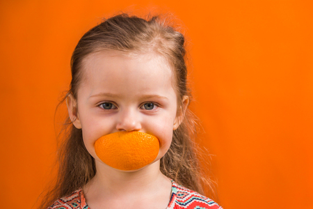 Little Girl Eating an Orangeの写真素材