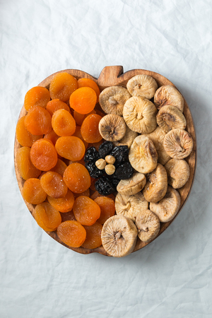 Dried fruits apricots figs prunes hazelnuts on a white background in the shape of an apple with space for text or titleの写真素材