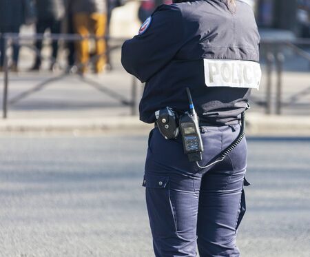 Policeman on a street in Paris controls public order. A fully equipped woman policeman monitors...