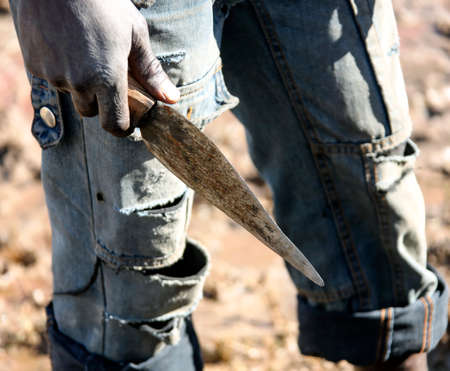 A makeshift primitive knife in the hand of a dark-skinned man. A simple carving knife in the right...