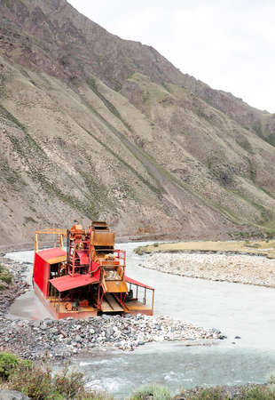 Small dredge on the river in the mountains of Asia. Draga is a floating mining and processing...