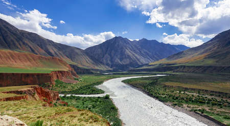 View of mountain valley with river and steppe pastures in the spurs of the Tien Shan. A typical sky landscape above the floodplain of mountain river with a right tributary.の写真素材