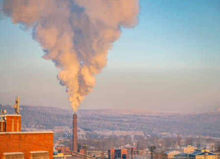 Air pollution by smoke from the pipe of a heat station in a Siberian city in winter. Clouds of smoky emissions against the sky on a frosty day.の写真素材