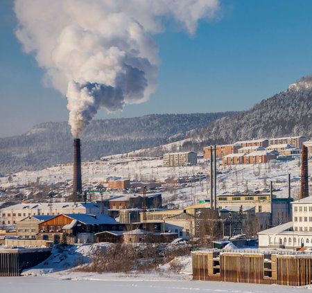 Smoke from thermal power plant in the north of the Irkutsk region on frosty day. Left bank of the Lena River near Ust-Kut, in December. Buildings and structures in the Rivermen area, in winter at temperature of minus 40 degrees Celsius.の写真素材